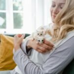 Woman holding sugar gliders on the sofa indoors.